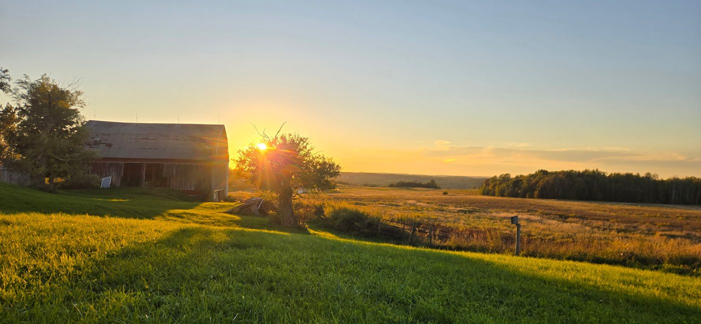 Sunset over an old barn and open fields on Adam’s farm in rural New York