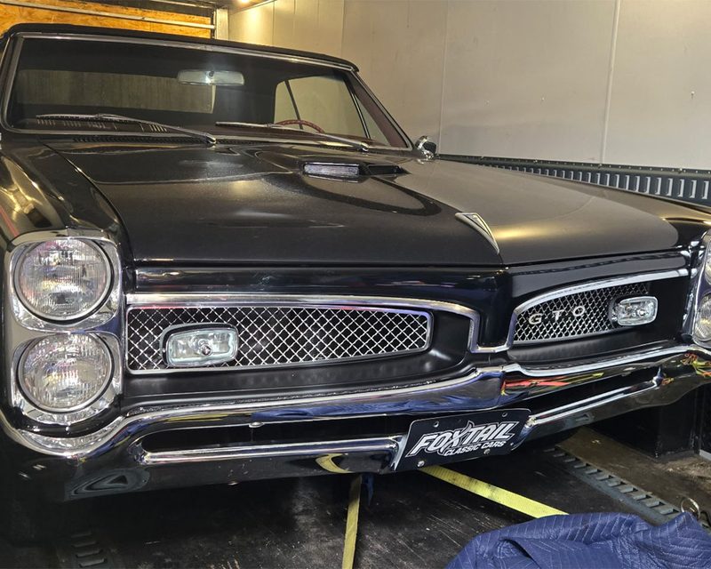 Black classic Pontiac GTO strapped down inside the enclosed trailer